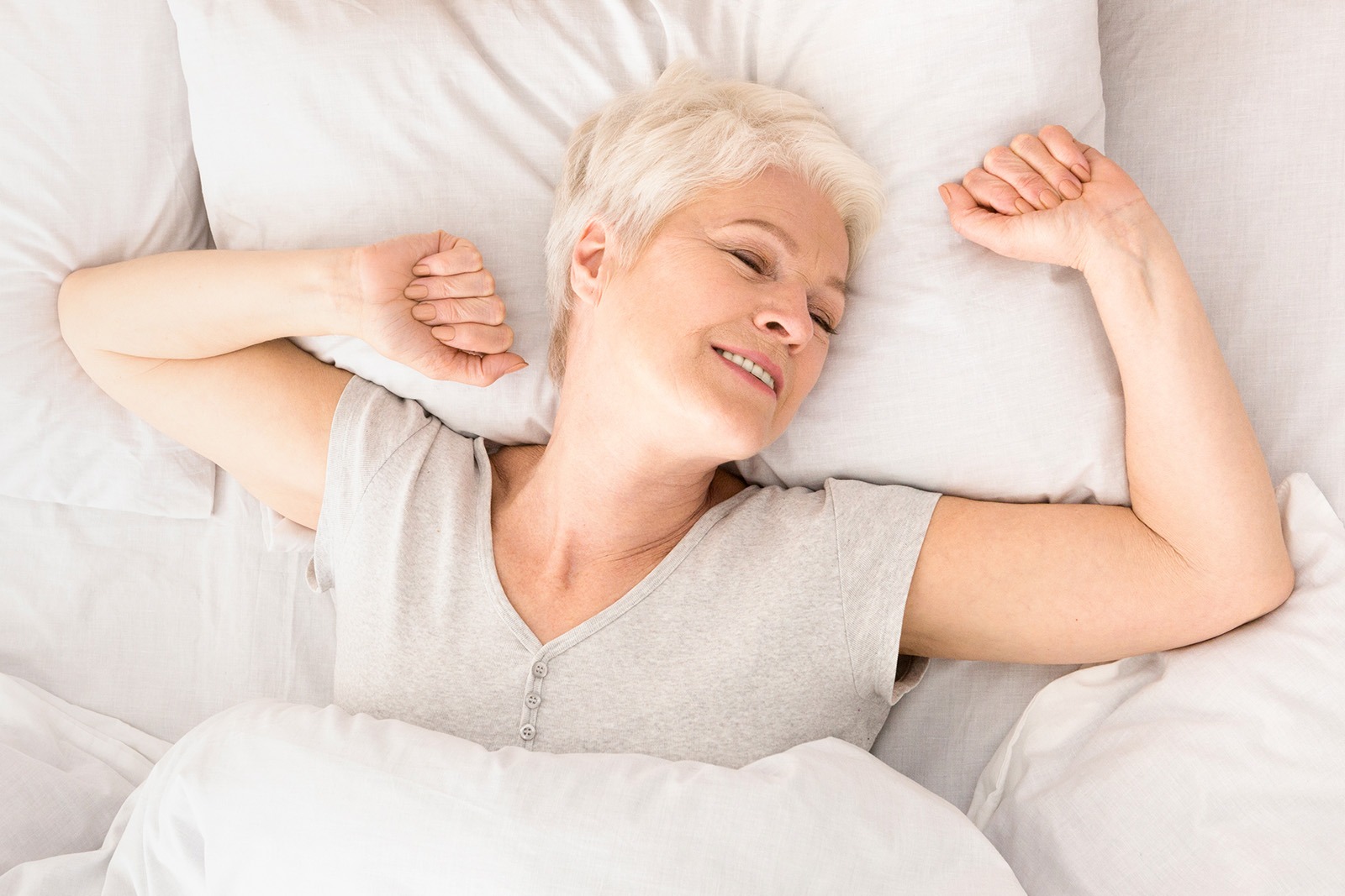 A senior woman stretching in bed